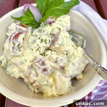 Creamy Red Potato Salad with Herbs and Dijon 9 Red potato salad in a bowl with a sprig of celery, a fork in the bowl and a napkin on the side.