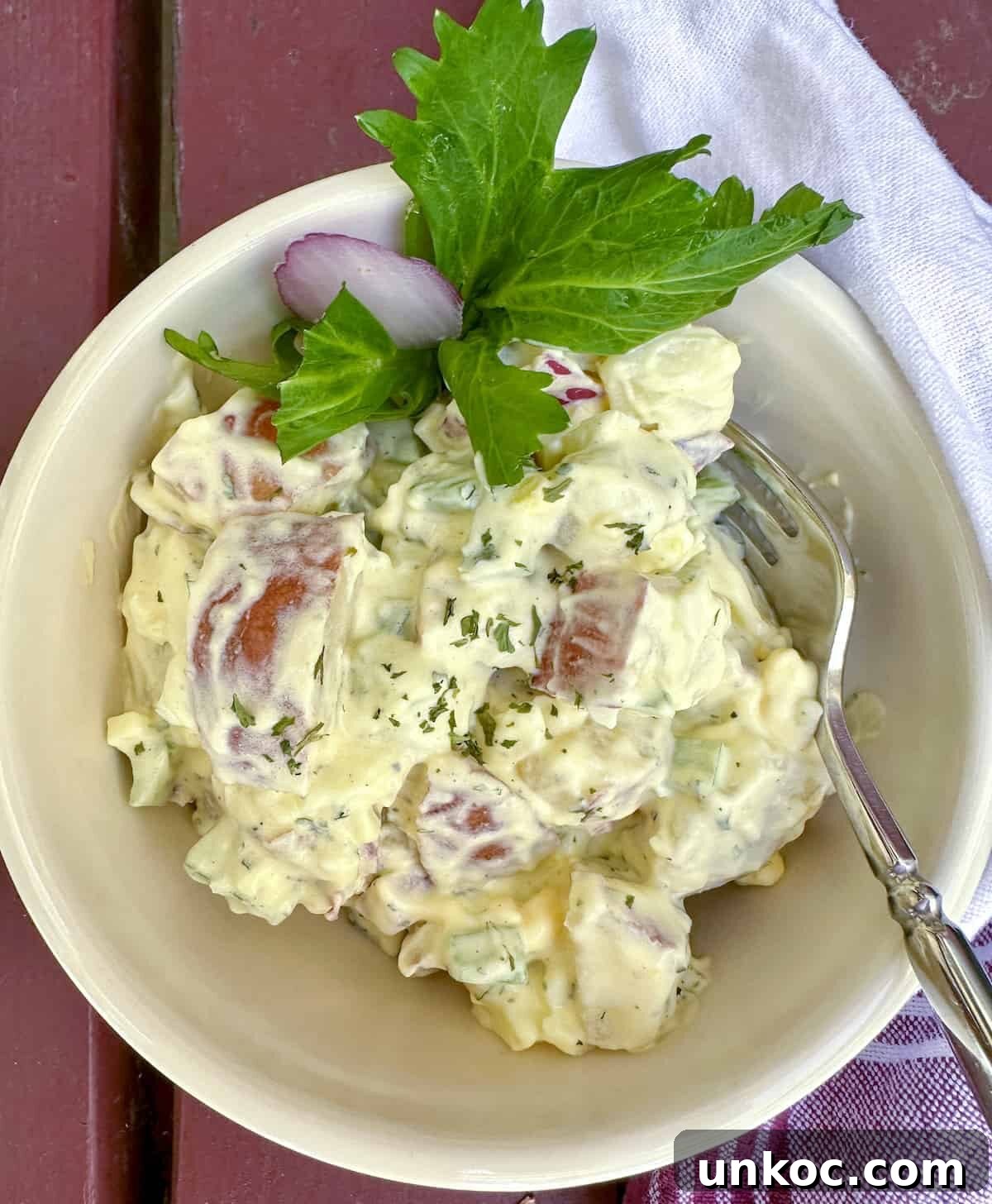 Creamy Red Potato Salad with Herbs and Dijon 8 Red potato salad in a small serving bowl with a fork on the side.