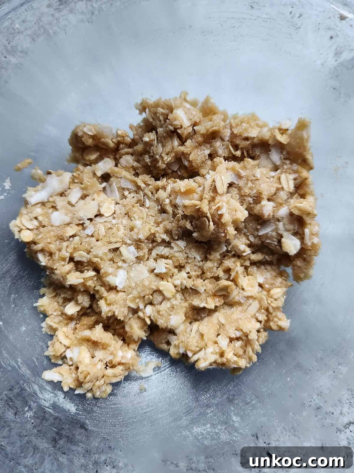 Batter for coconut oatmeal cookies in a clear bowl.