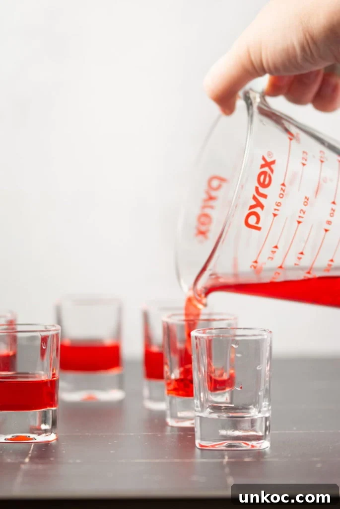 5 Ingredient Red White and Blue Jello Shots 5 Pouring red Jello into shot glass.