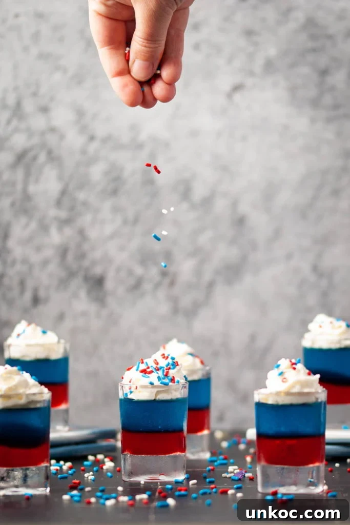 5 Ingredient Red White and Blue Jello Shots 7 adding patriotic sprinkles on top of whipped cream on jello shots
