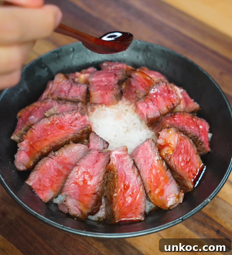 Japanese Steak Donburi Rice Bowl Recipe 7 Spoon drizzling sweet-savory glaze over seared steak slices arranged on a bowl of white rice.