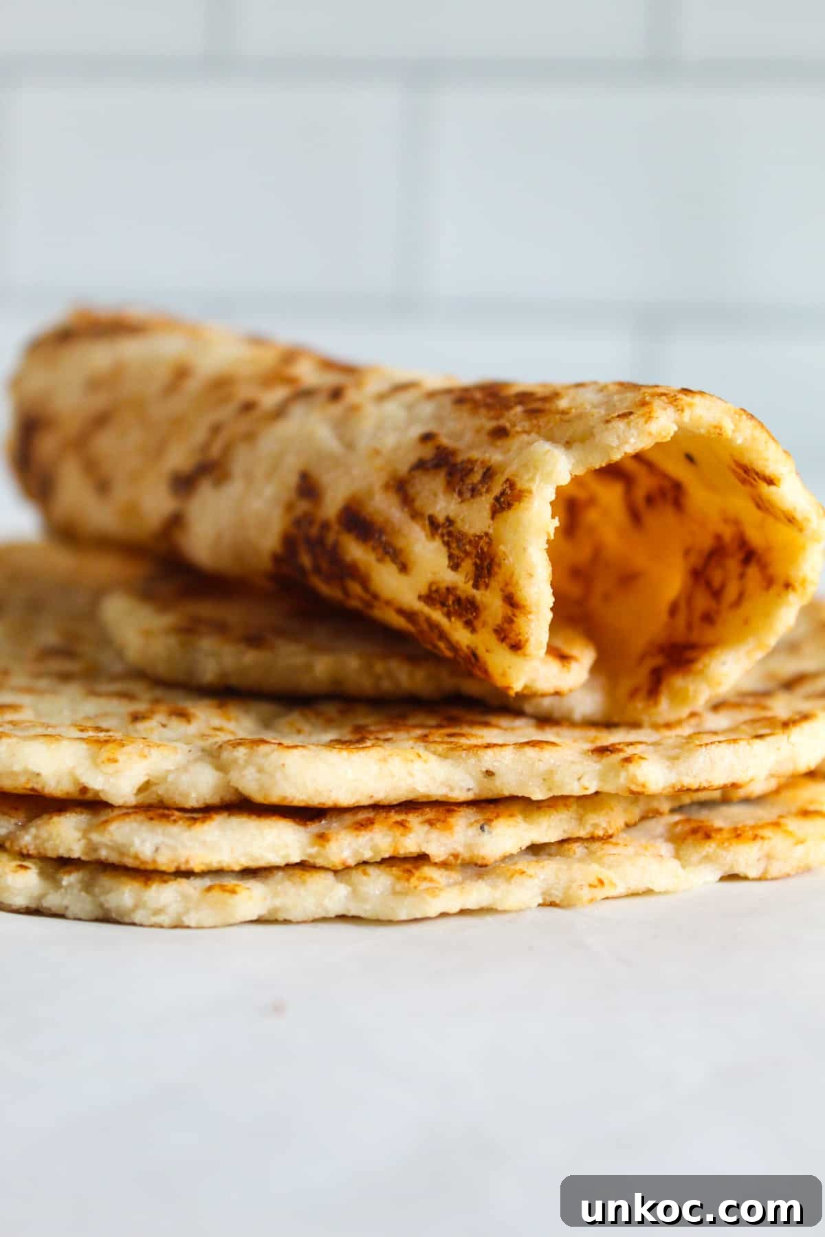 Soft Keto Almond Flour Tortillas That Fold Without Cracking 2 rolled almond flour tortilla sitting on a stack of tortillas