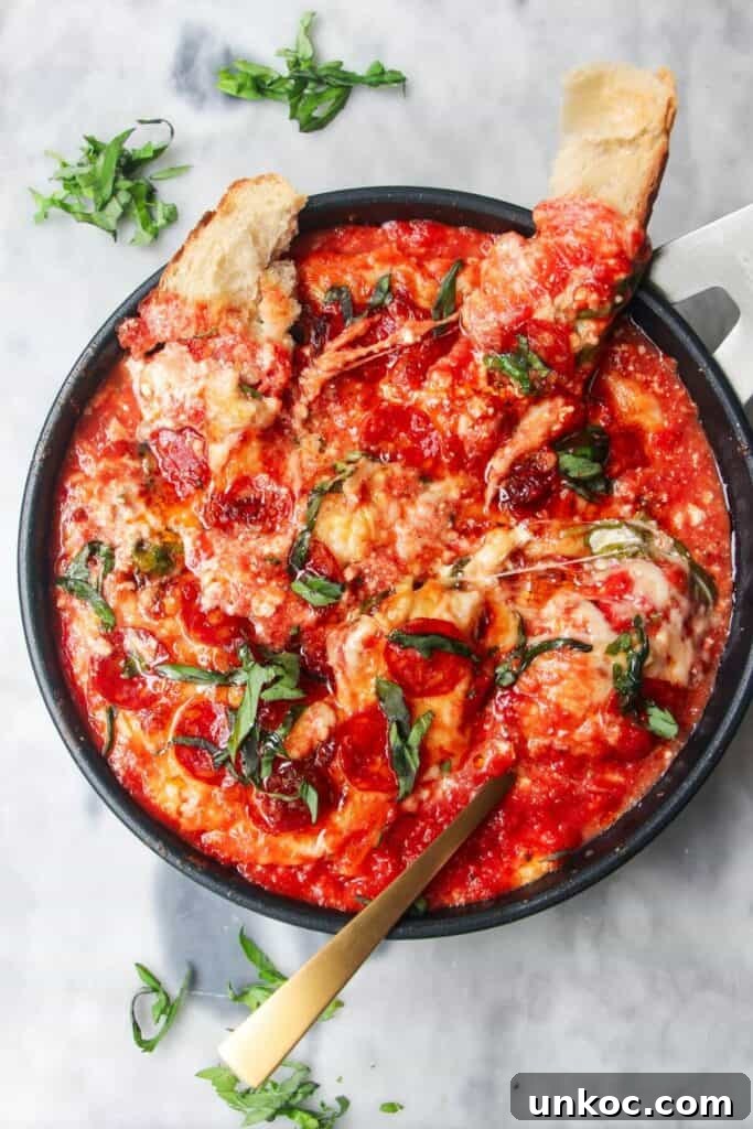 Spicy Harissa Whipped Feta Dip 12 Cheesy pepperoni topped pizza dip with two pieces of bread and a spoon inside.