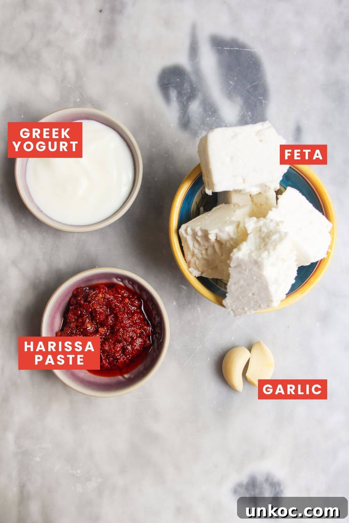 Spicy Harissa Whipped Feta Dip 3 Ingredients for spicy feta dip laid out on a marble background and labelled.