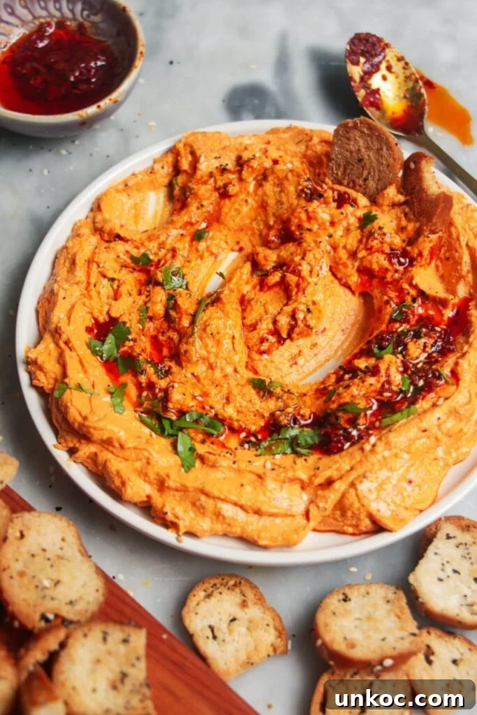 Spicy Harissa Whipped Feta Dip 8 Spicy harissa feta dip on a small white plate, with bagel chips and more harissa on the side.