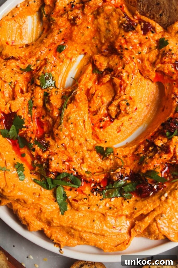Spicy Harissa Whipped Feta Dip 9 Close up of spicy feta harissa dip on a small white plate with harissa and parsley on top.