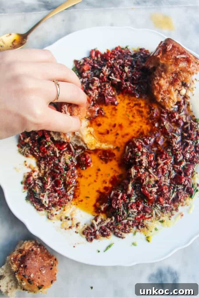 Spicy Harissa Whipped Feta Dip 10 Hand swirling piece of bread through olive oil dip on a large white plate.