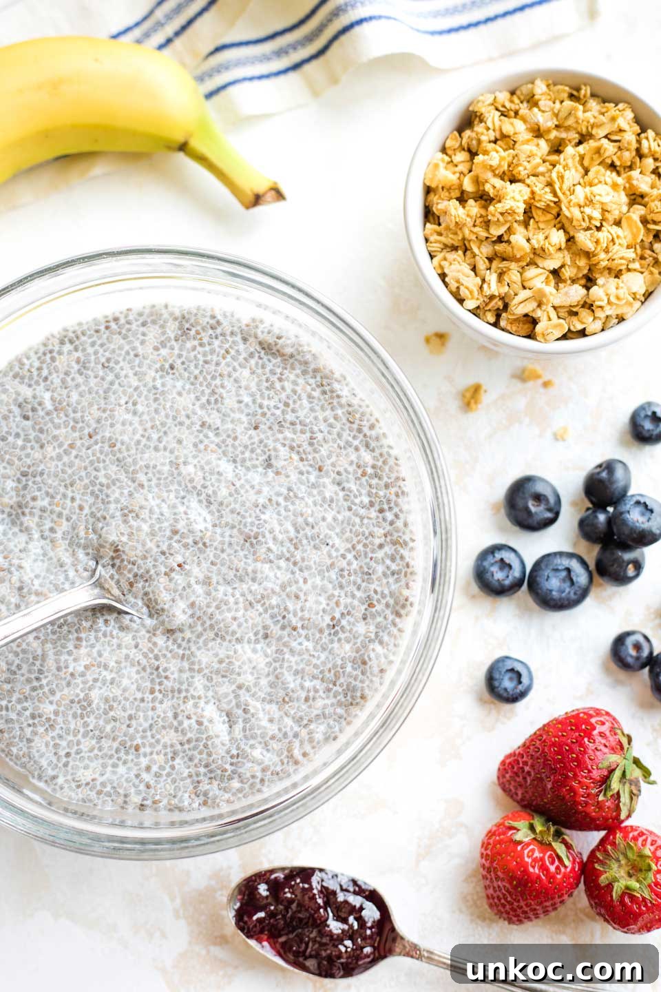Toppings for Chia Pudding with Coconut Milk serving bowl with finished chia pudding, surrounded by toppings like fruits, granola and jelly