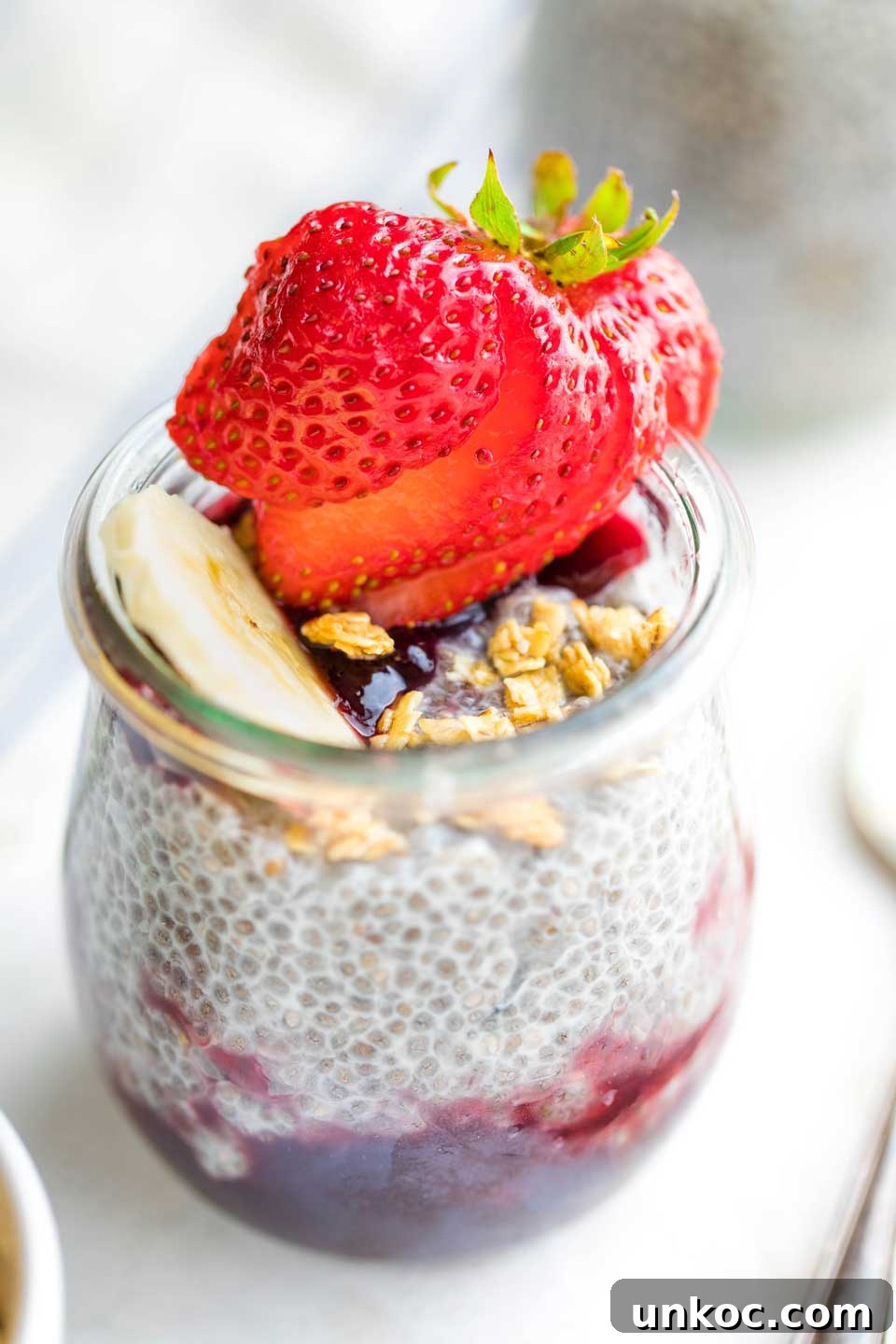 Make Ahead Chia Pudding Recipe for Meal Prep closeup of individual serving of chia pudding in glass tulip jar, topped with a strawberry and granola