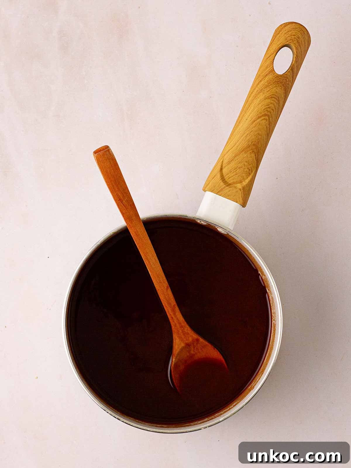 A pan with Peking sauce with a wooden spoon for step 4 in the recipe for Slow Cooker Peking Duck.