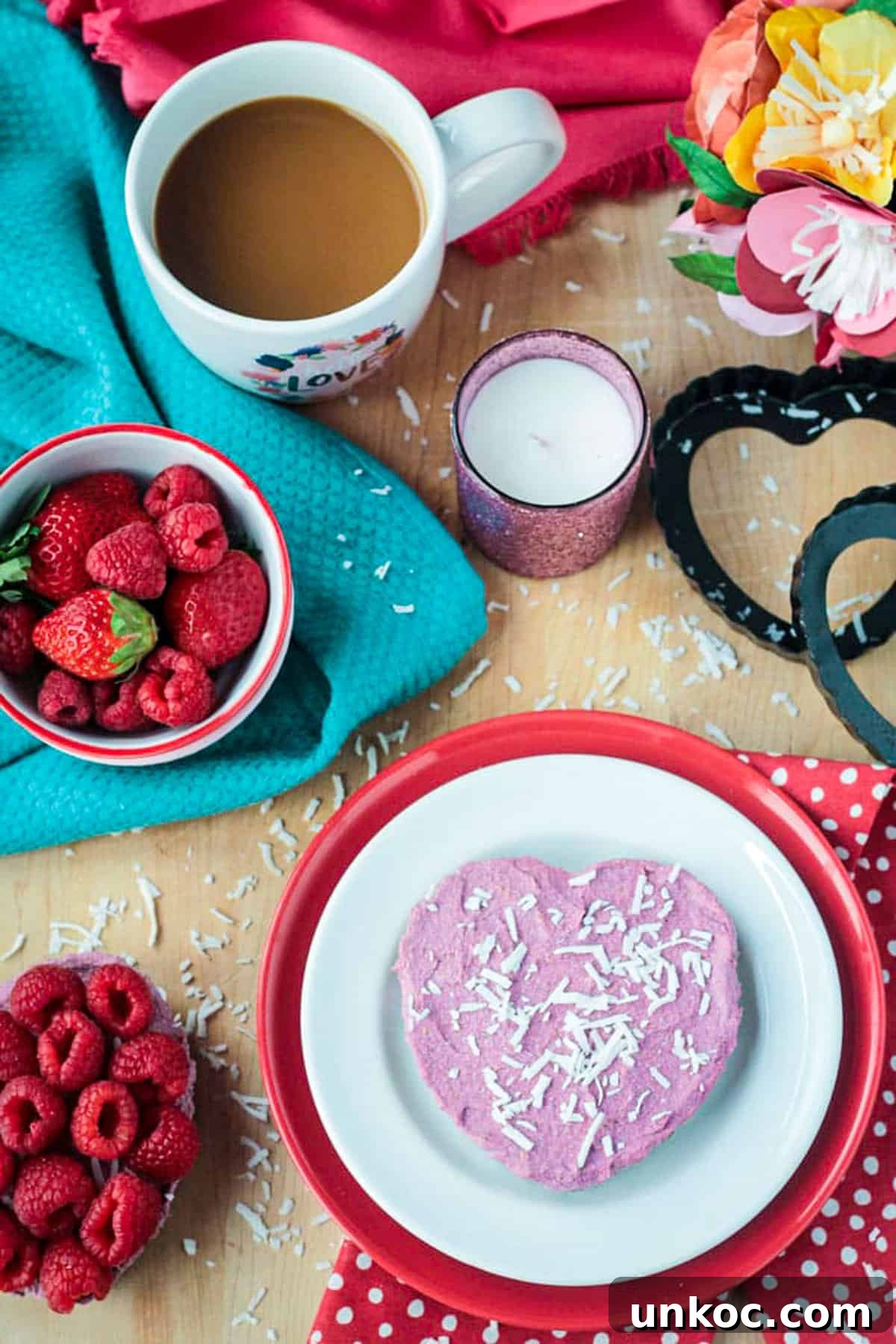 No Bake Vegan Raspberry Cheesecake Tarts One heart shaped raspberry vegan raw cheesecake tart on a white and red plate.
