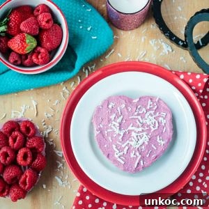 Vegan Raw Raspberry Cheesecake Recipe 8 One heart shaped vegan raspberry cheesecake tart on a white and red plate.