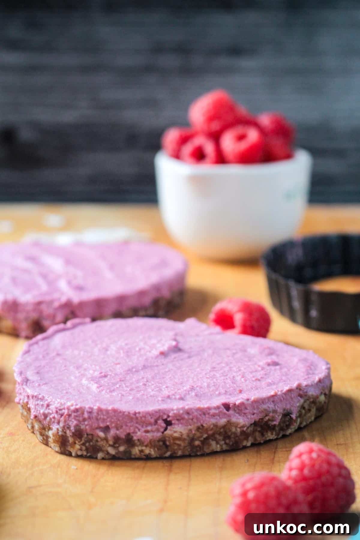 No Bake Vegan Raspberry Cheesecake Tarts Side view of a tart showing where the crust and filling meet.