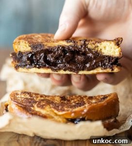 close up shot of hand lifting French toast sandwich showing filling
