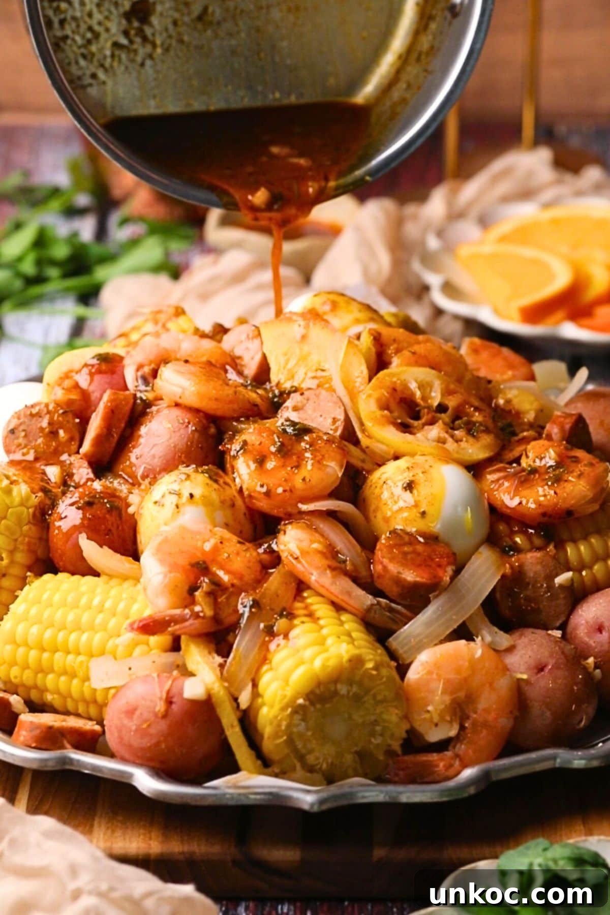 Cajun Shrimp Boil with Corn and Potatoes 9 cajun shrimp boil on a platter with cajun butter sauce being poured on top.