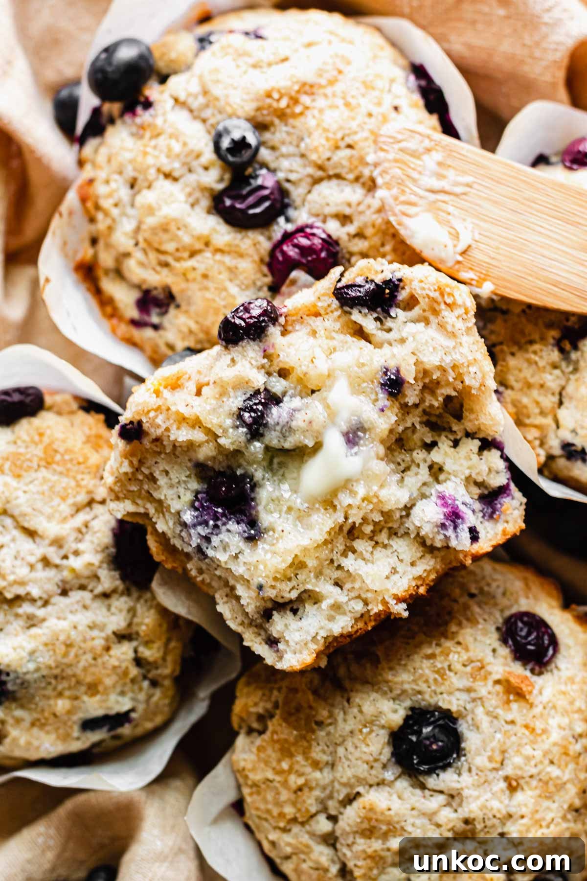 Close up of a blueberry muffin split in half with melted butter spread on it.