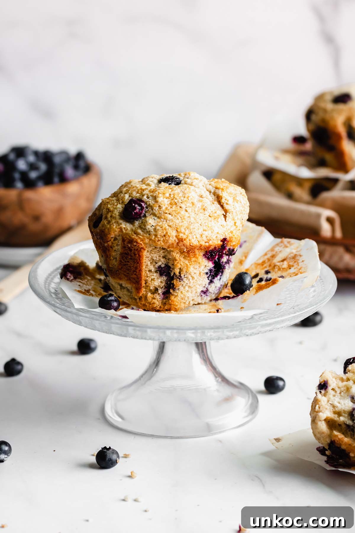One jumbo blueberry muffin on a small pedestal cake stand.
