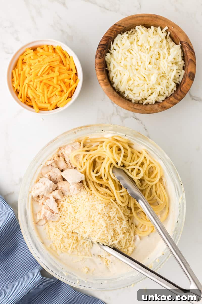 Chicken Tetrazzini with Cream of Mushroom Soup 7 Spaghetti noodles and chicken, with parmesan cheese are added to the creamy mixture in bowl.