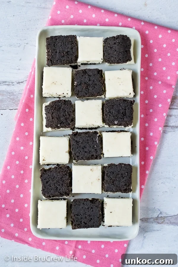 Coconut Oreo Fudge - adding an Oreo cookie crust to this coconut cream fudge makes it taste incredible. Make this easy recipe for spring or summer parties! #fudge #coconut #Oreocookies #nobake #spring #Easter #dessert #coconutcream Multiple pieces of white coconut fudge with an oreo cookie base on a white plate.