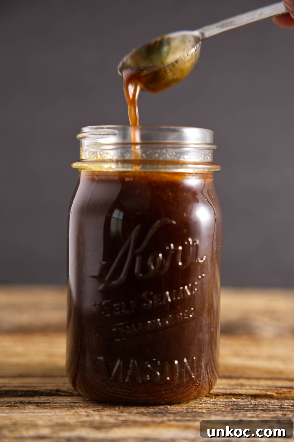 Pouring pork loin marinade for smoker into glass Mason jar.