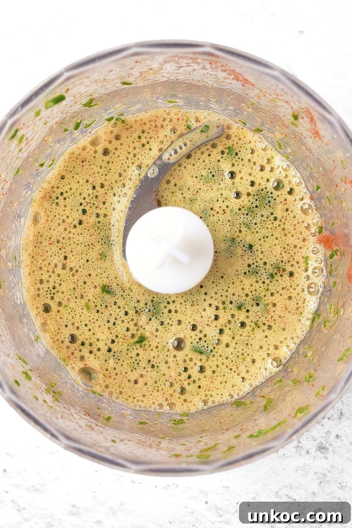 Processed frothy yellow liquid in food processor.