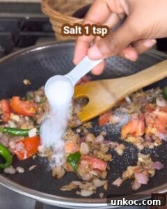 Jaffna Eggplant Chickpea Curry Sri Lankan Brinjal Recipe 23 Adding salt to Jaffna brinjal curry in a skillet with vegetables.
