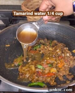 Jaffna Eggplant Chickpea Curry Sri Lankan Brinjal Recipe 27 Tamarind water being added to a flavorful brinjal curry in a wok, highlighting the traditional Sri L.