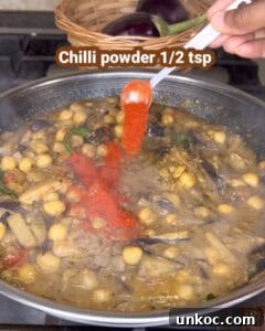 Jaffna Eggplant Chickpea Curry Sri Lankan Brinjal Recipe 37 A close-up of cooking Jaffna brinjal kadala curry with chickpeas, eggplants, and spices in a traditi.