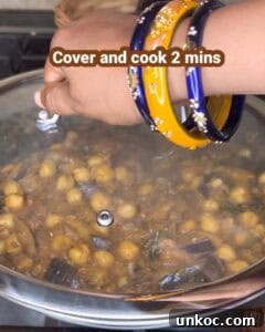 Jaffna Eggplant Chickpea Curry Sri Lankan Brinjal Recipe 38 Cooking Jaffna brinjal and chickpeas curry in a pot with a hand covering it.
