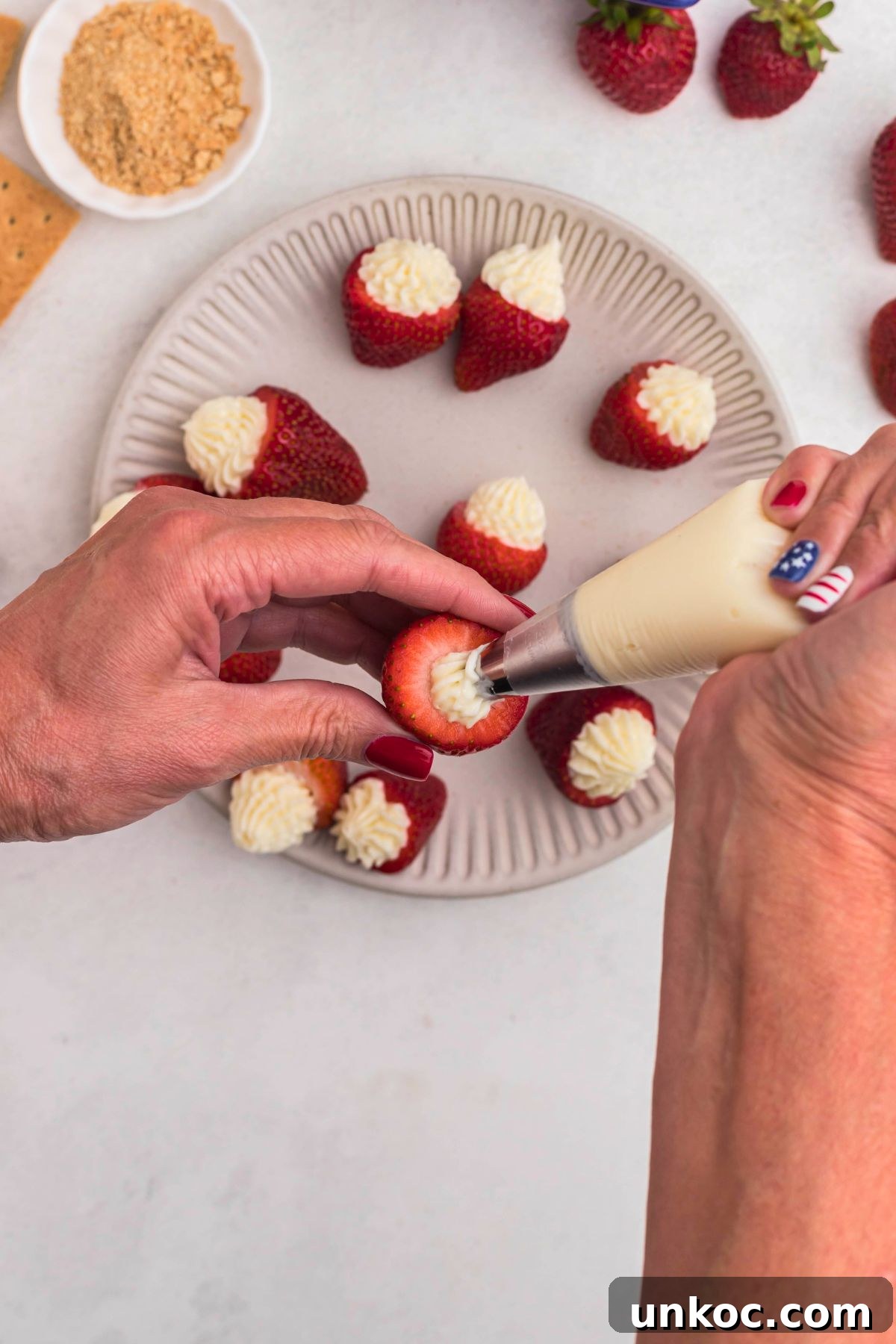 Cheesecake Stuffed Strawberries Recipe 6 Cream cheese filling in a piping bag being used to fill cut out strawberries.