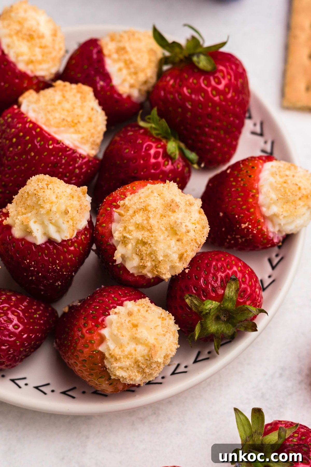 Cheesecake Stuffed Strawberries Recipe 8 Strawberries stuffed with cheesecake filling on a small white plate.