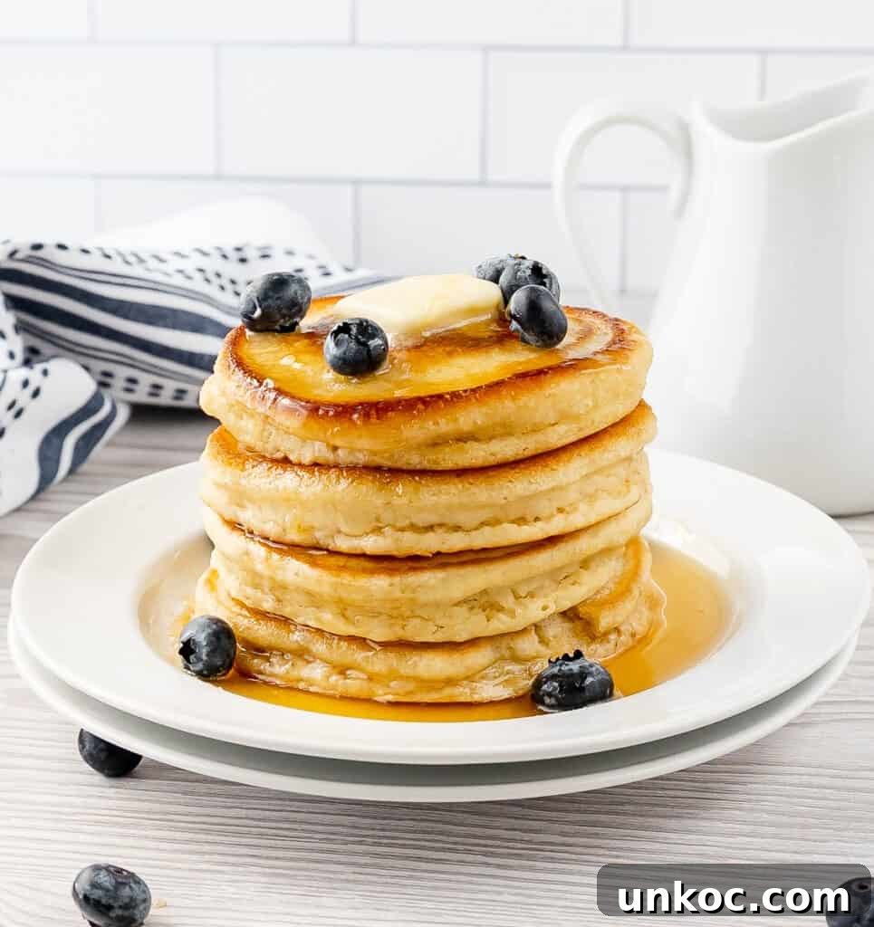Fluffy Oat Milk Pancakes Recipe 2 A stack of fluffy oat milk pancakes with syrup and blueberries
