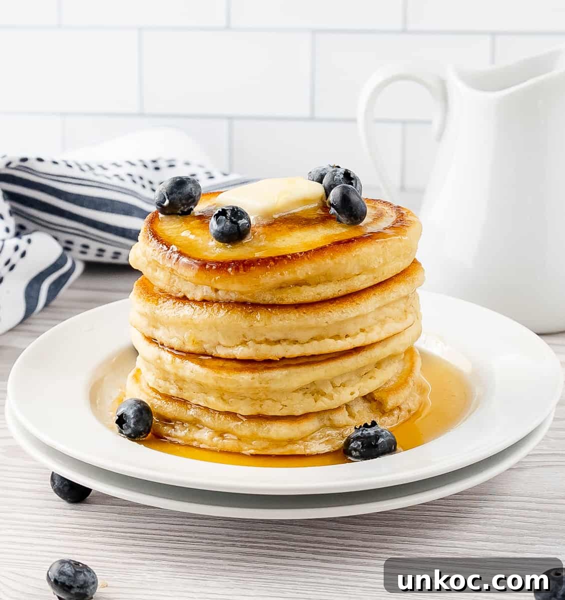 Fluffy Oat Milk Pancakes Recipe 9 A stack of fluffy oat milk pancakes with syrup and blueberries