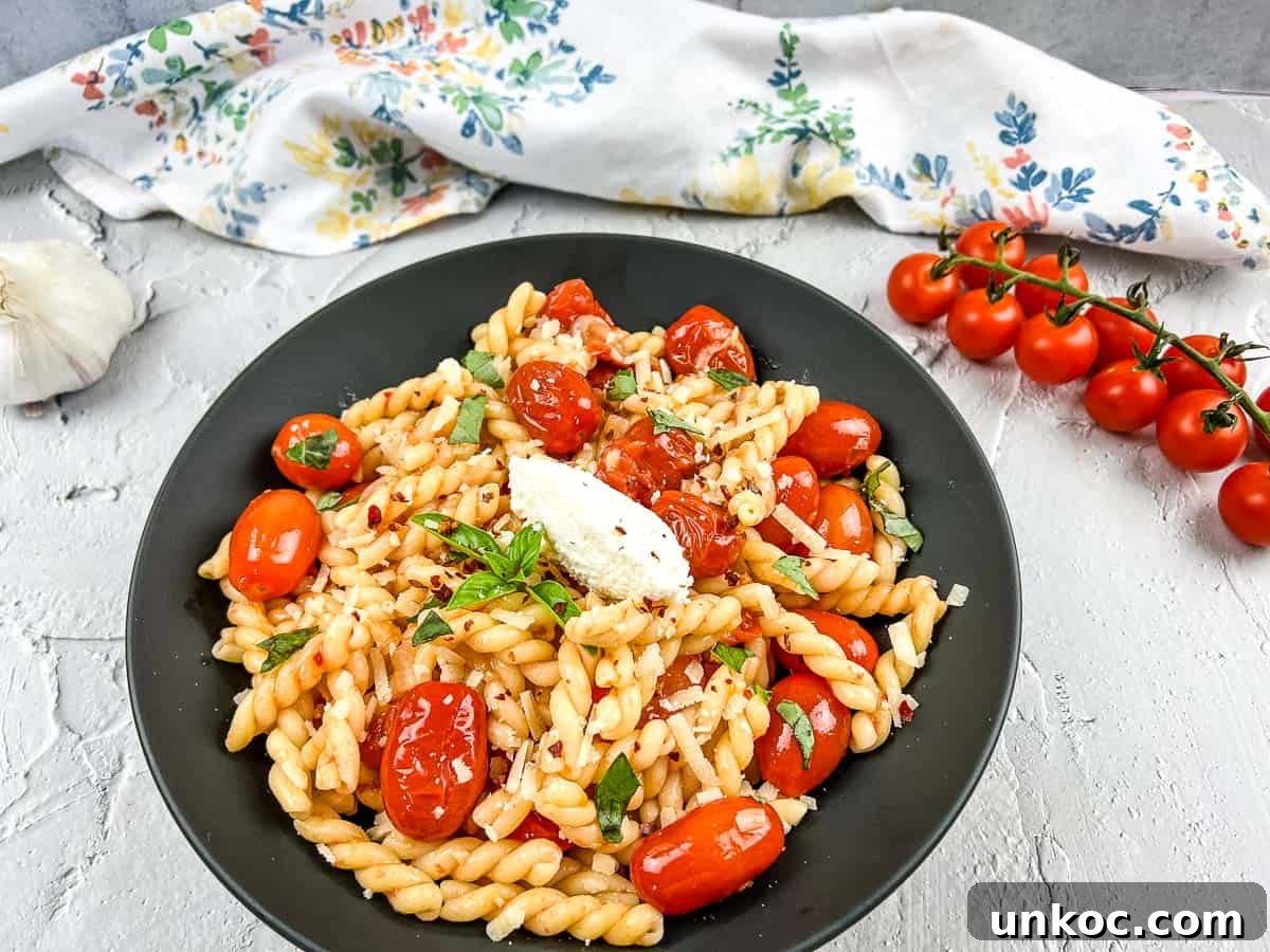A bowl of Pasta with Fresh Cherry Tomato Sauce, alongside cherry tomatoes and garlic.