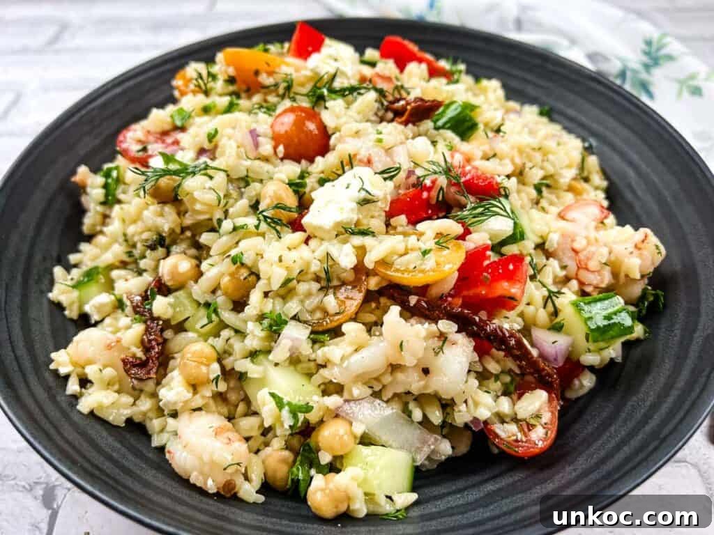 A bowl of Mediterranean orzo salad on a black plate.