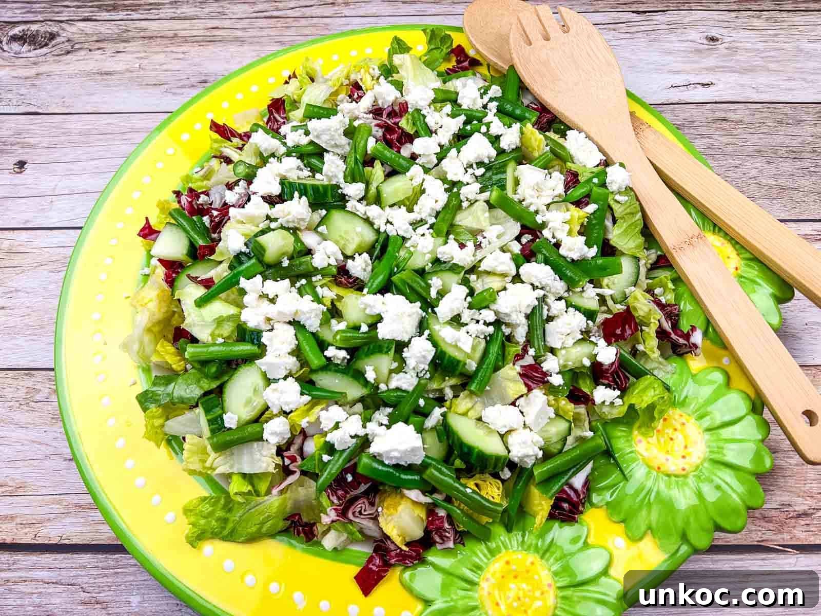 Mediterranean Chopped Salad with crumbled feta cheese, on a yellow plate with flower designs.