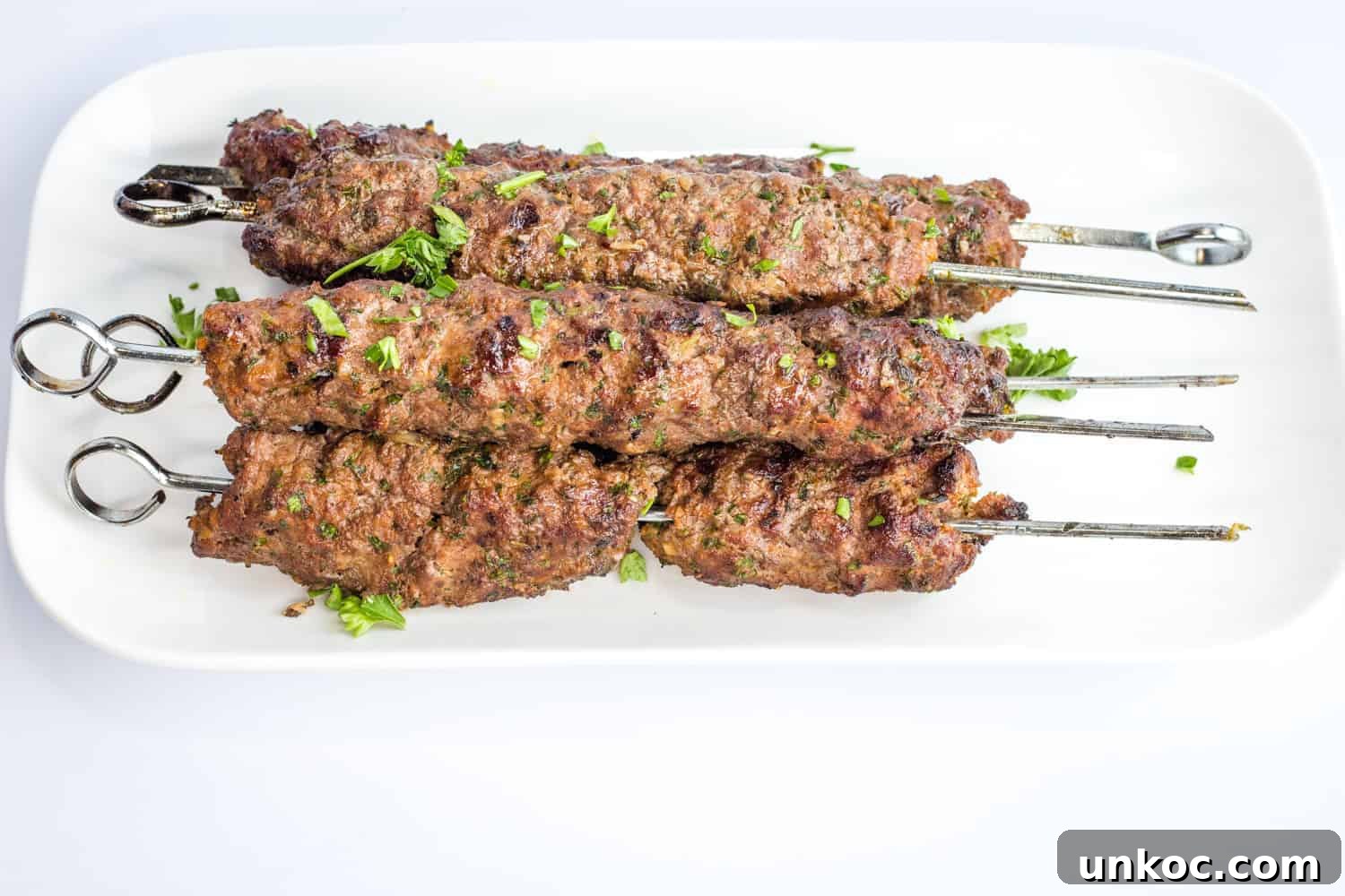 Kefta Beef Kabobs stacked on a white platter.