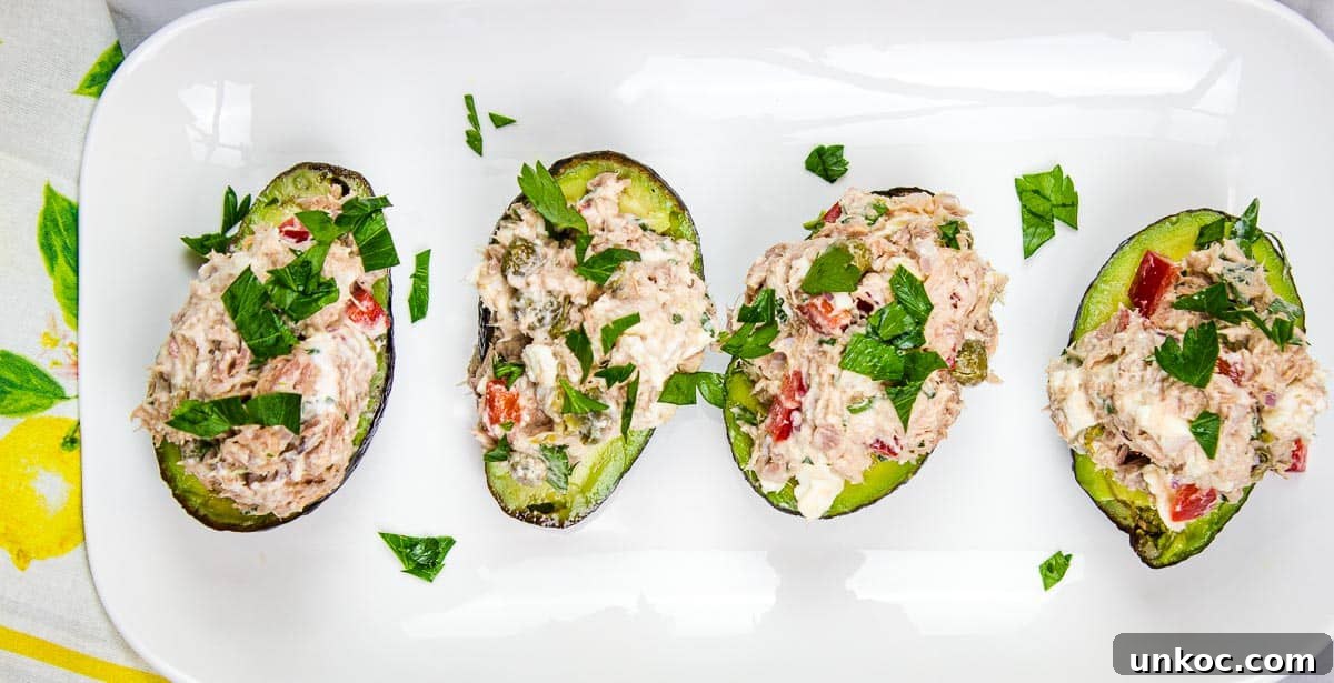 Four Mediterranean Tuna Salad stuffed avocados on a white plate.