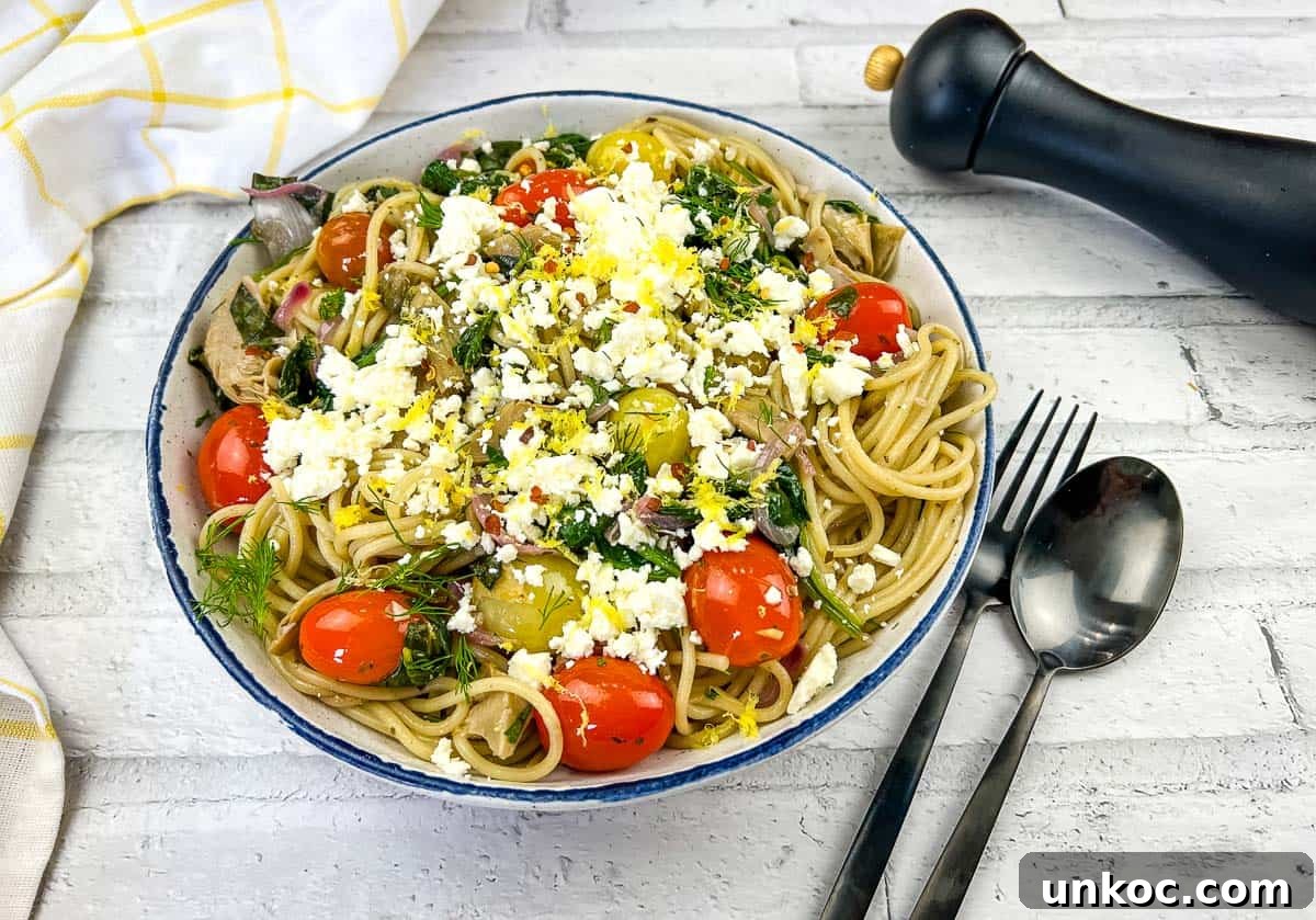 A bowl of pasta with tomatoes, feta and kalamata olives.