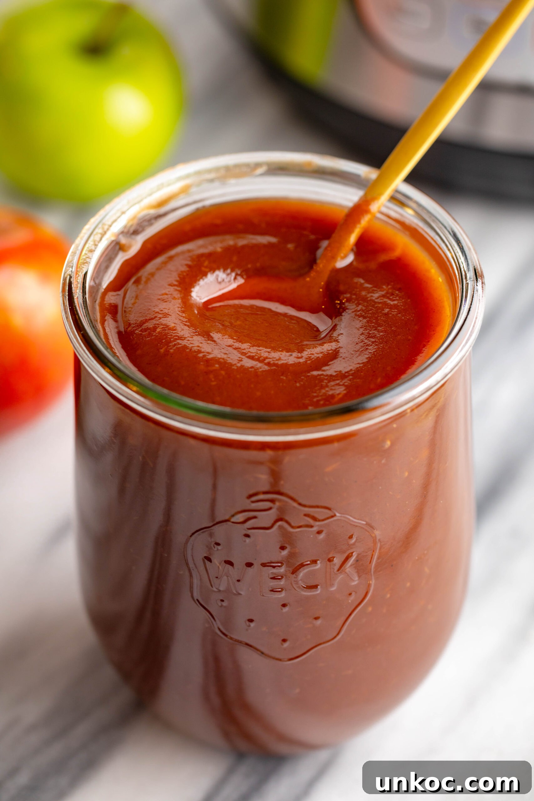 Instant Pot Apple Butter Recipe No Peeling Required 4 weck jar filled with apple butter and a gold spoon