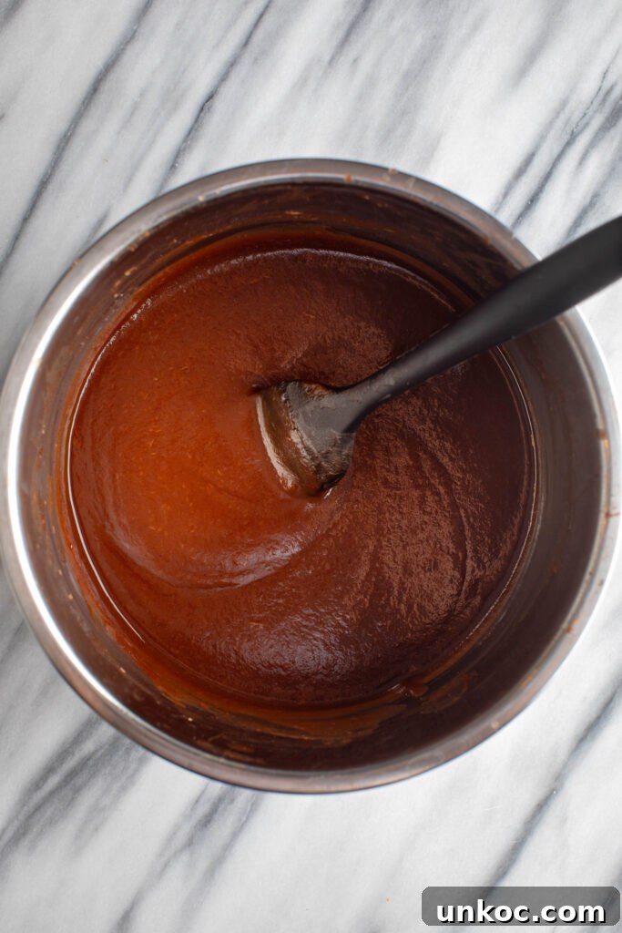Instant Pot Apple Butter Recipe No Peeling Required 9 blended apples, maple syrup, vanilla extract and lemon juice mixed thoroughly in a silver bowl with a black spatula